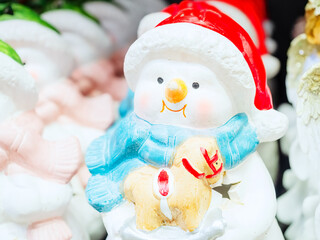 White decorative ceramic figurine of a snowman on a blurred background. Close-up photo