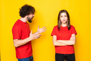 Young couple quarrel screaming standing isolated over yellow background