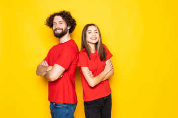 Young couple holding hands crossed, looking at each other posing isolated on yellow orange background. People lifestyle concept.