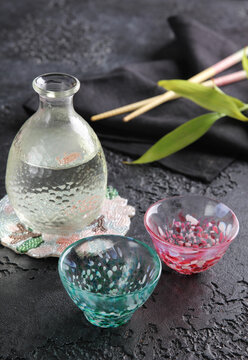 Japanese cuisine. National alcoholic drink in Japan. Syake sake in a transparent decanter jug  with bowls on a black table with chopsticks. Restaurant menu. Background image, copy space