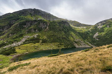 Fototapeta premium green hills with a mountain lake while hiking