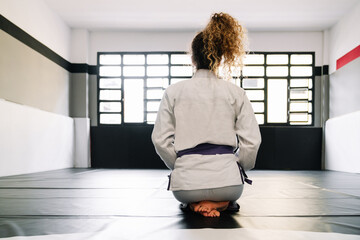 Portrait of a girl on her back kneeling on the floor mat of a gymnasium that practices martial arts...
