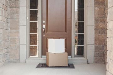 Contactless delivery service for online order. Cardboard boxes lying on porch by front home door. Contact free delivery for self-isolation at home. Healthy shopping in coronavirus pandemic.