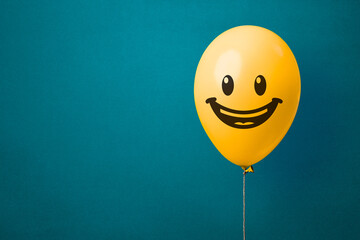 Stock photo of a yellow balloon with smiling face on a blue background