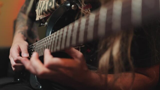 Closeup Of Guitar Strings And Neck. Guitarist Playing Rock, Metal By Beautiful Eight String Guitar In The Room With Neon Lights.