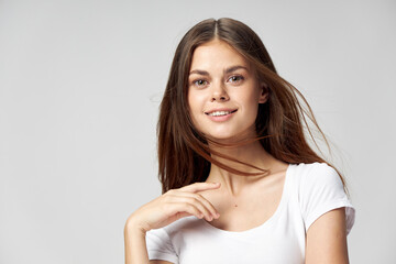 Fototapeta premium woman in a white T-shirt holds a hand near the neck and smiles front view 