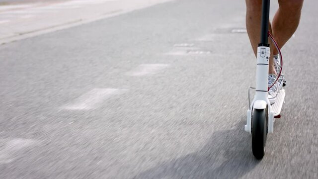 Midsection of commuter riding electric scooter outdoors in city, ecologic transport concept.