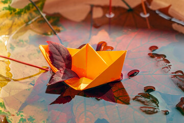 Origami paper boat and scenic fallen leaves in a water. Concept of bright fall