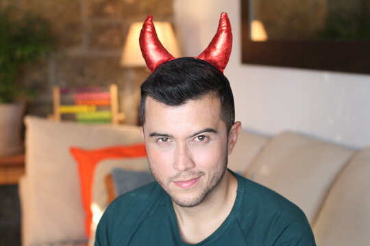 Young ethnic man with devil horns at home 