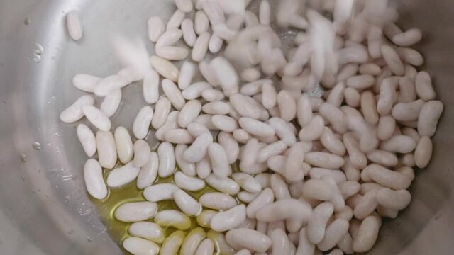 White Beans Falling At Slow Speed In Pressure Cooker To Make Bean Stew With Chorizo And Bacon.