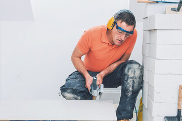 middle aged male worker installing large format tiles on wall