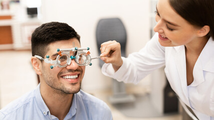 Optometrist checking patients vision with trial frame