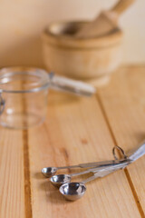 Measurement spoons set made of stainless steel against neutral wooden background