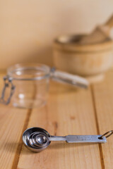 Measurement spoons set made of stainless steel against neutral wooden background