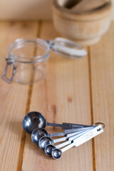 Measurement spoons set made of stainless steel against neutral wooden background