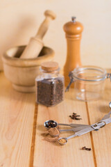 Measuring spoons and other kitchen utensils with spices, with neutral textures and colors against wooden background
