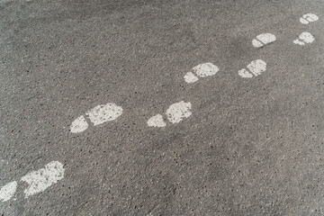 Footprints of shoes with white paint on the asphalt. Background texture