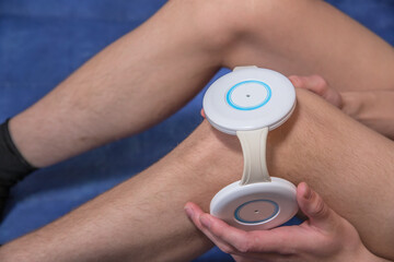 A person treats the knee joint with an electromagnetic therapy device.