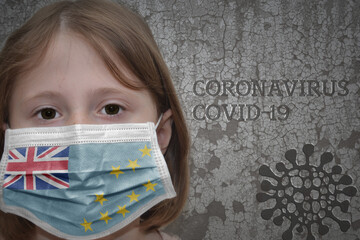 Little girl in medical mask with flag of Tuvalu stands near the old vintage wall with text...