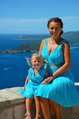 Fototapeta na wymiar Daughter and mom in identical dresses against the background of the sea.