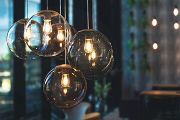 Beautiful and cosy luxury light lamp. Cosy cafe, coffee shop or lounge interior. Vintage and minimal decor. Retro vibes. Many different vintage light bulbs hanging from ceiling, coffee shop interior