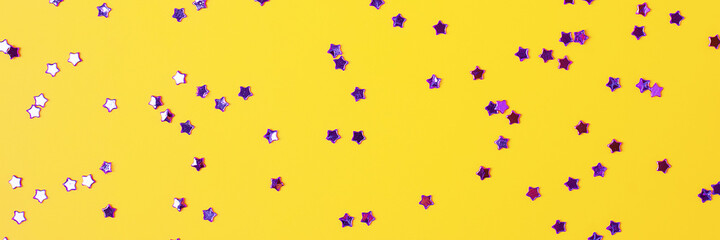 Violet confetti on yellow. Colorful Christmas or holiday background