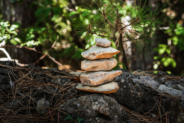 Pyramid stones balance on a tree trunk in the forest. Pyramid in focus, forest background is blurred.