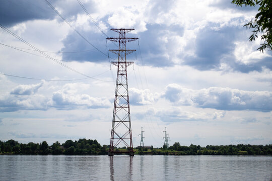 High voltage transmission power tower, electricity pylon stand on piles in water. Steel tower, used to support overhear power line. Nature landscape. Daugava river, Latvia