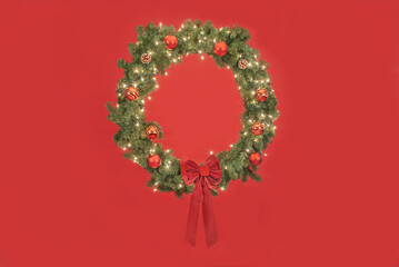 christmas wreath with lights and decoarations on a red background
