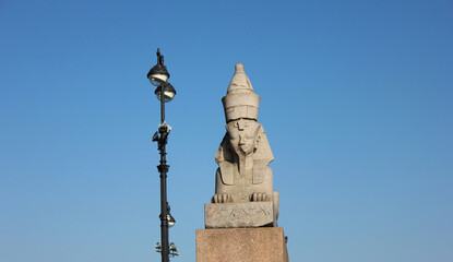 Old egyptian Sphinx on quay with Sphinxes in Saint Petersburg, Russia. Historic city landmark, ancient sphinx statue isolated on empty blue sky background. St Petersburg scenic attraction view