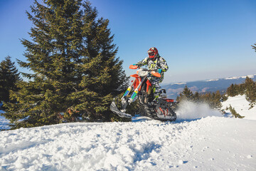 Snowbike rider in mountain valley in beautiful snow powder. Snowdirt bike with splashes and trail....