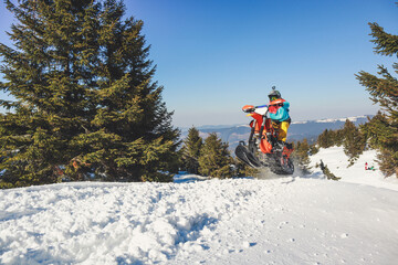 Snowbike rider in mountain valley in beautiful snow powder. Snowdirt bike with splashes and trail. Snowmobile winter sport riding
