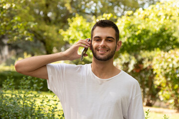 Obraz premium attractive young man with beard talking on mobile phone outdoors