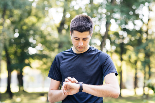 Caucasian man in sports uniform using smartwatch to measure speed, distance, heartbeet caring about physical body health. Futuristic technology. Mock up