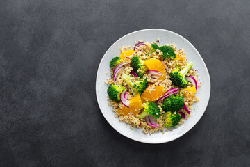 Vegan quinoa and broccoli warm salad with oranges and fresh onion, top down view
