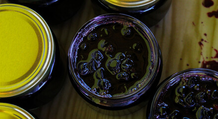 Homemade chokeberry jam. Full jars of homemade chokeberry jam on a tray. Aronia jam.
