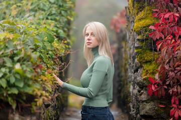 Beautiful blonde in a garden of Virginia creeper in autumn
