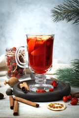 New year's drink mulled wine surrounded by spices, pine branches, cinnamon sticks, red berries and dried lemons on a wooden background. Holiday background. The concept of New year and Christmas.