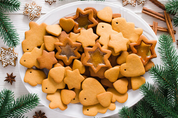 Plate full of freshly baked Christmas gingerbread ready to decorate with icing on white background.