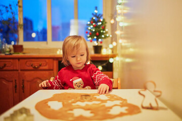 Adorable little toddler girl cooking Christmas cookies