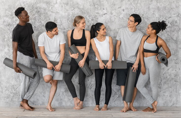 Fototapeta na wymiar Sporty Lifestyle. Group of multiracial people resting with yoga mats before training