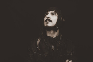 Male portrait in retro style. young man in the vintage aviation costume on the black background
