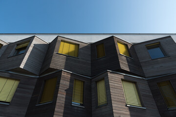 Yellow roller blinds on a wood-paneled facade