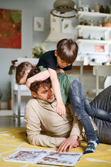 Young father reading book with two little sons oon the floor, happy parent playing with kids and spending time together