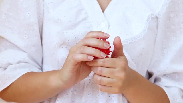Close-up of a nervous girl's hands playing with an antistress toy in a shape of red virus ball 