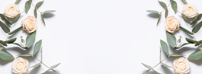 Long wide banner with beautiful light pink roses and eucalyptus twigs on white background with copy space for your text. Invitation or congratulation card concept.