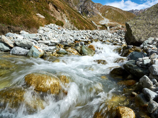 a swift mountain river with white streams of water rushes among the stones