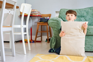 Young preschool boy play with pillow and have fun at home