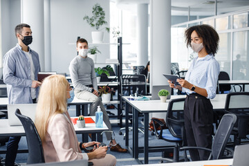 Corporate meeting and group work in company. African american woman manager in protective mask...