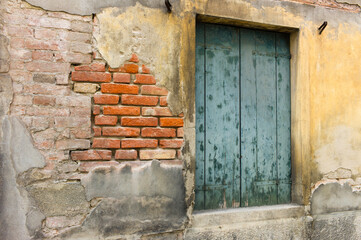 Pale green wooden door in a dilapidated red brick wall and yellow and brown plaster in a house in...